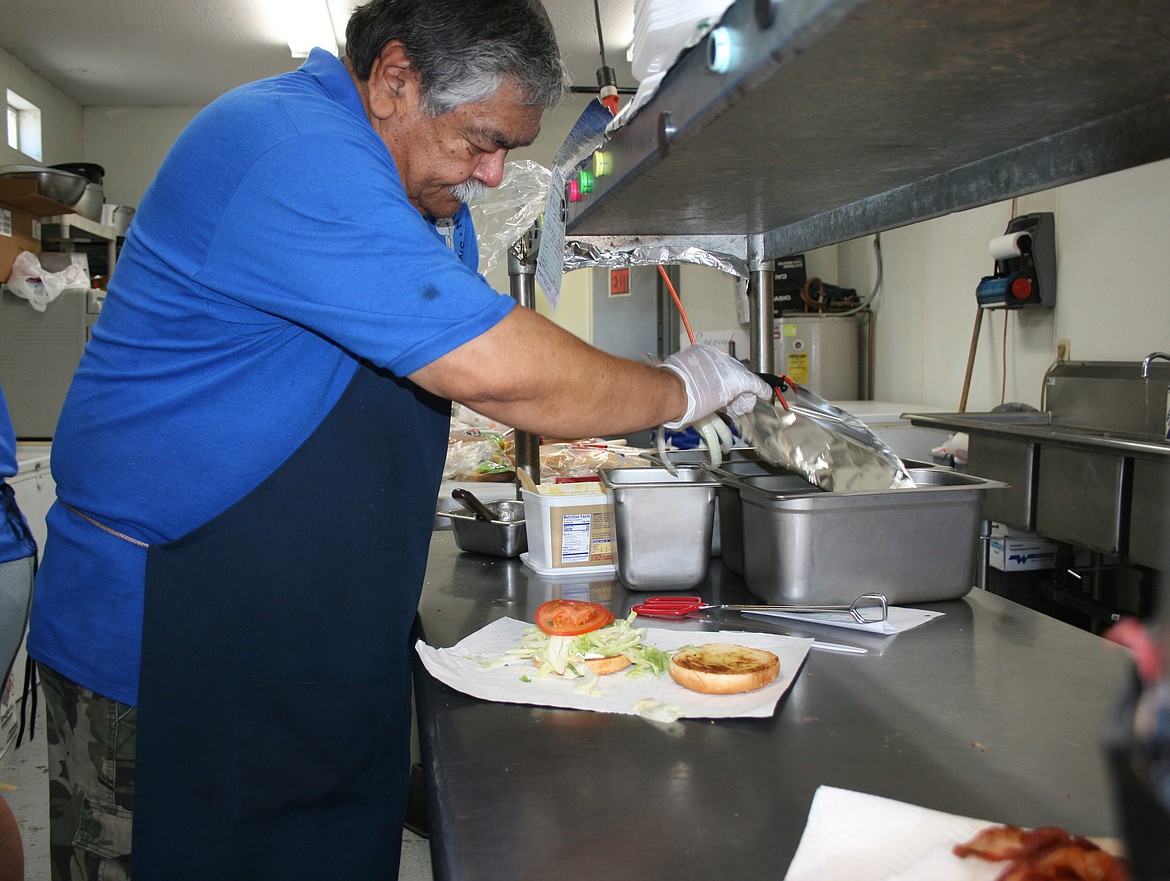 Jim Duzon, owner of Top Gun concessions, adds toppings to a hamburger. Duzon and his wife Joy are looking at a new way to promote their business, since many of their regular customers are closed in 2020.