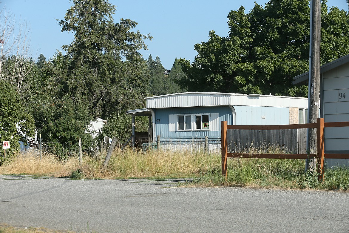 A for-sale mobile home in Chateau Mobile Home Village in Post Falls sits among tall grass on Thursday evening. Some residents of the mobile home park have been experiencing problems with access to water, causing one resident to leave a jug under a dripping sink just to have water on hand. (DEVIN WEEKS/Press)