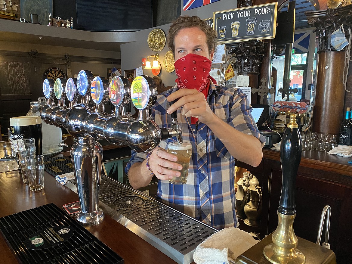 The Crown and Thistle Pub employee Chase Turney pours up a beer while following the mask mandate.