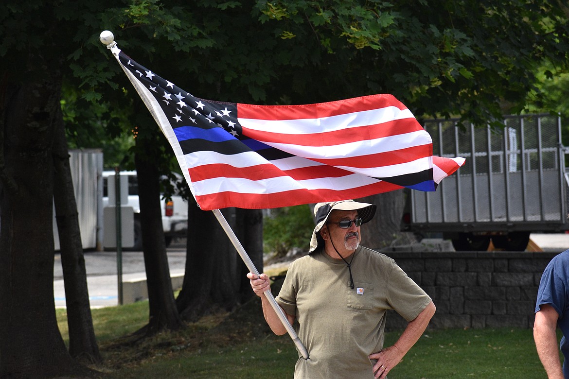 (Photo by DYLAN GREENE) 
 A man holds up a flag to show support for local law enforcement on Saturday.