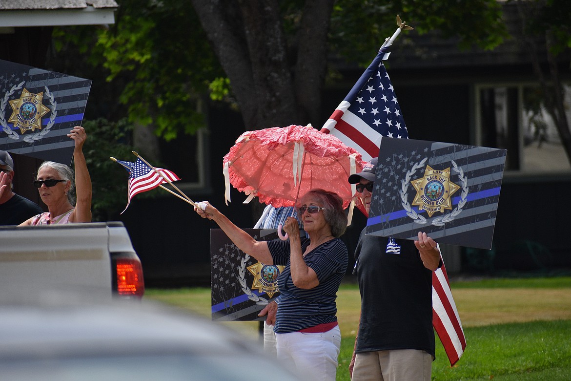 (Photo by DYLAN GREENE)
People wave American flags and hold up signs during Saturday’s event.