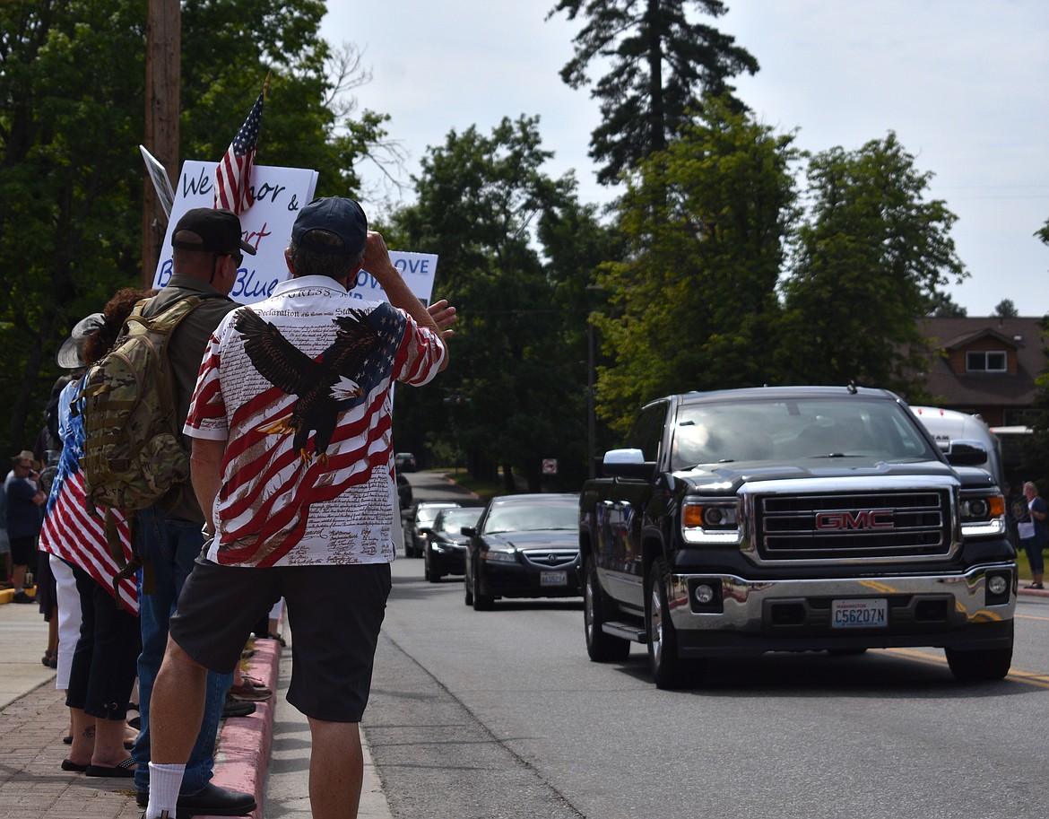 (Photo by DYLAN GREENE) 
 People wave to cars passing by the county courthouse Saturday.