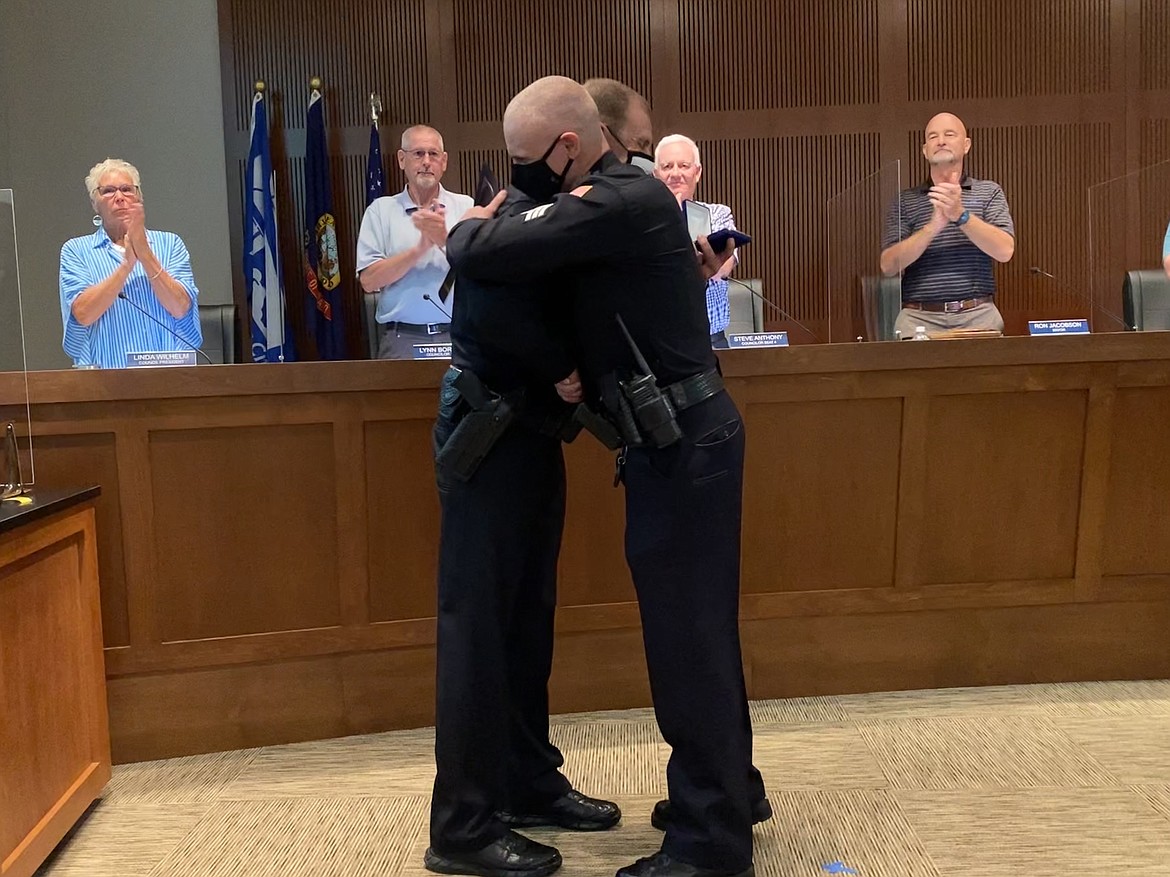 Post Falls Police Department Captain Jason Mealer (left) and Sergeant Justin Anderson (right) shake hands and embrace after Anderson was given the Purple Heart award at Tuesday night’s city council meeting. (MADISON HARDY/Press)