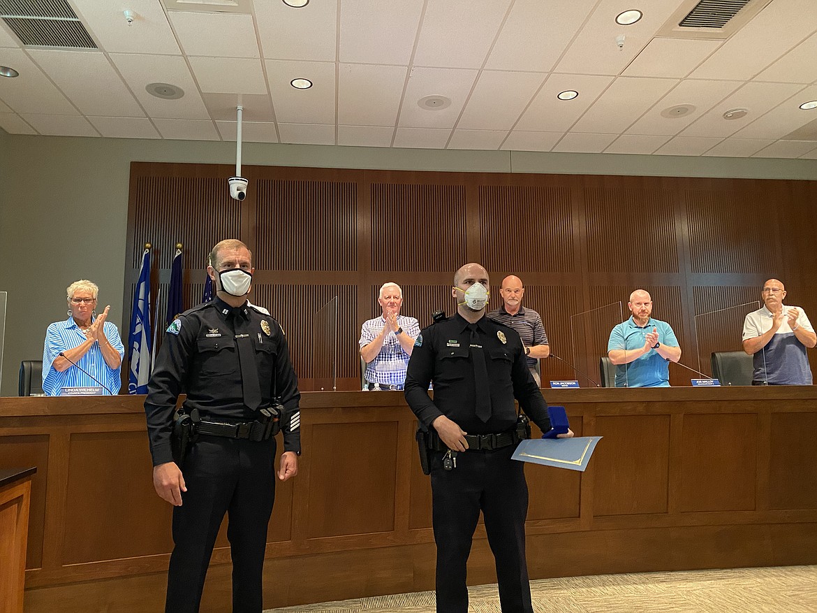 Post Falls Police Department Captain Jason Mealer (left) and Officer Lukas Crigger (right) receive a standing ovation after Crigger received the Life-Saving Award at Tuesday night’s city council meeting. (MADISON HARDY/Press)