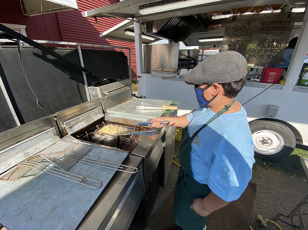 Alexander James White, son of the owner of White's Concessions, fries up some curly fries at the North Idaho State Fair Food Fix Friday evening. (MADISON HARDY/Press)