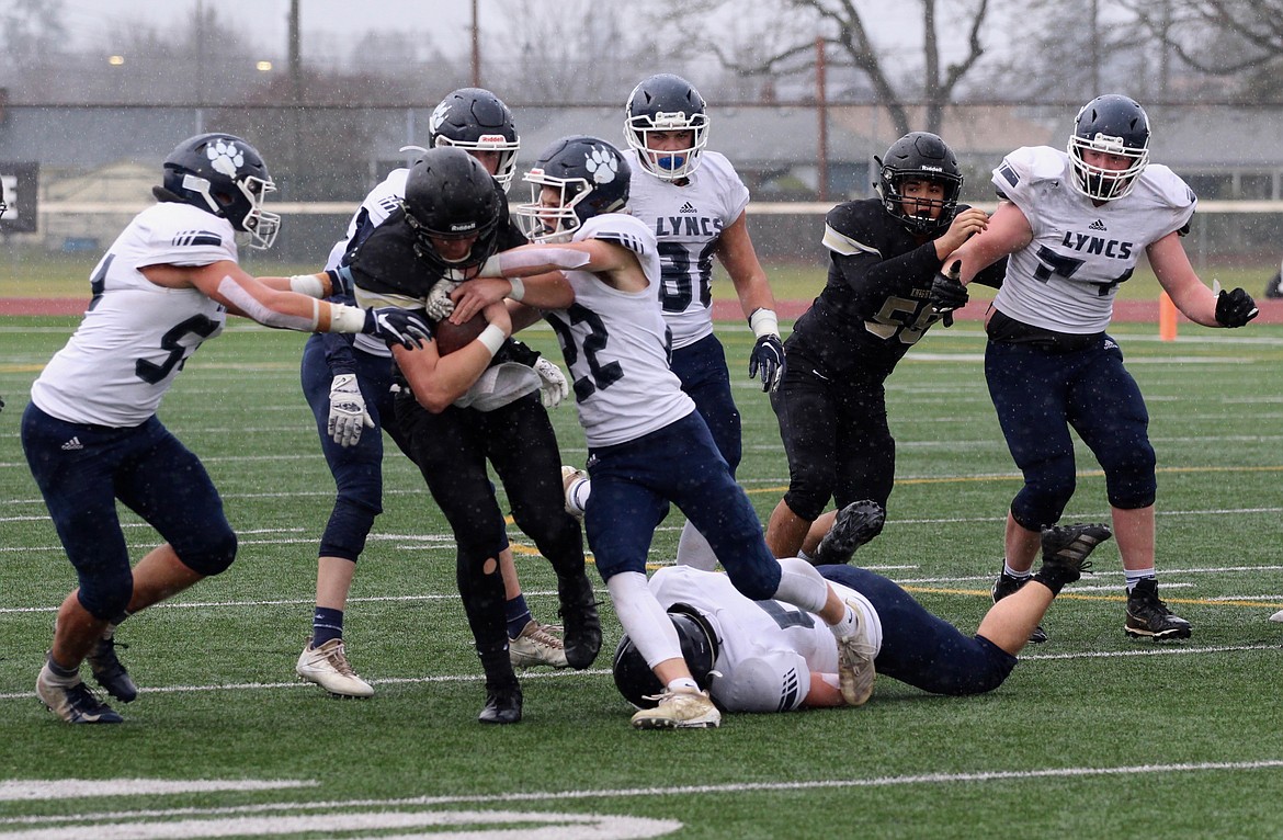 Casey McCarthy/Columbia Basin Herald Lorenzo Myrick pushes forward as the Lynden Christian players swarm to make the tackle in the first half on Saturday.