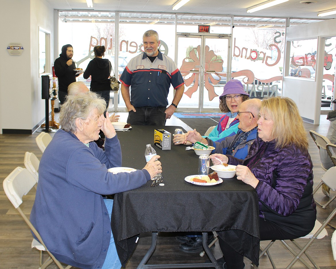 Scott Myers (standing) owner of Scotty’s Auto Repair, talks with customers during the grand opening at his new location Thursday.