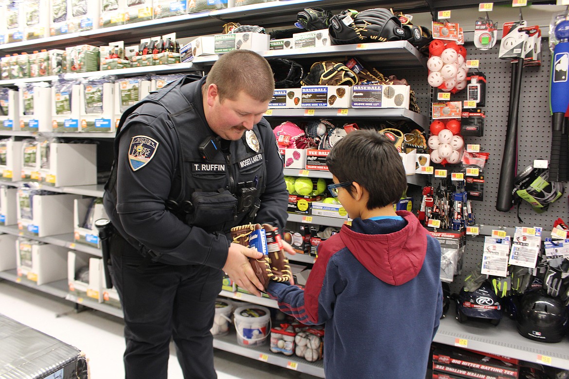 Ulizes Hernandez (right) and his shopping buddy Travis Ruffin of the Moses Lake Police Department check the fit of a baseball glove for Ulizes during the eighth annual ‘Shop with a Cop’ Wednesday.