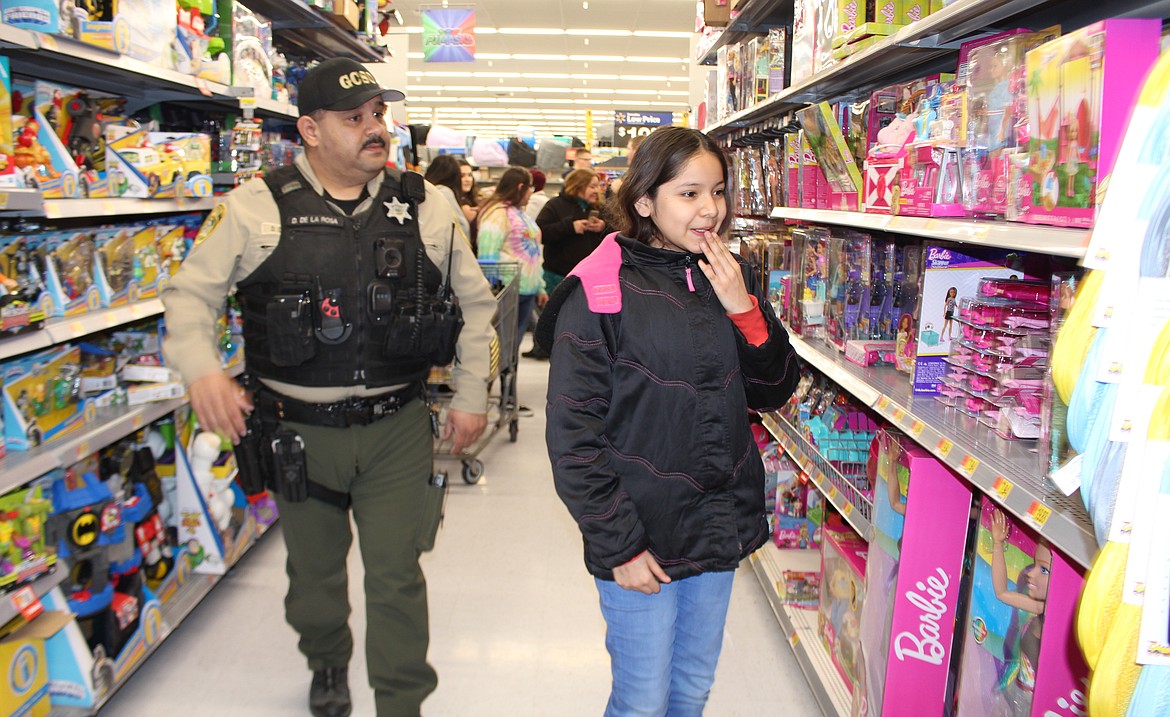 Delia Miranda and her shopping buddy Dave DeLaRosa of the Grant County Sheriff’s Office look over the options in the doll aisle during the eighth annual ‘Shop with a Cop’ Wednesday.