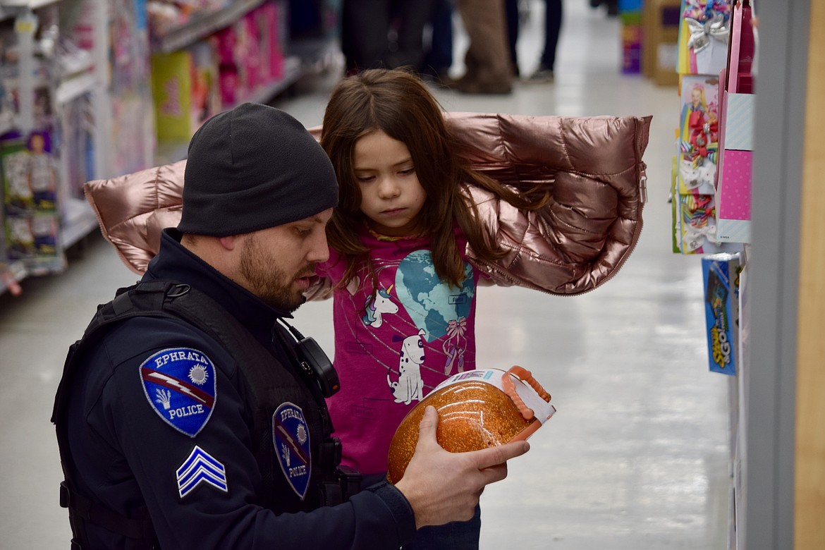 Ephrata Police Detective Todd Huffman confers with 6-year-old Anna Ramirez about a possible present for her sister during the Shop With a Cop event at the Ephrata Walmart on Wednesday.