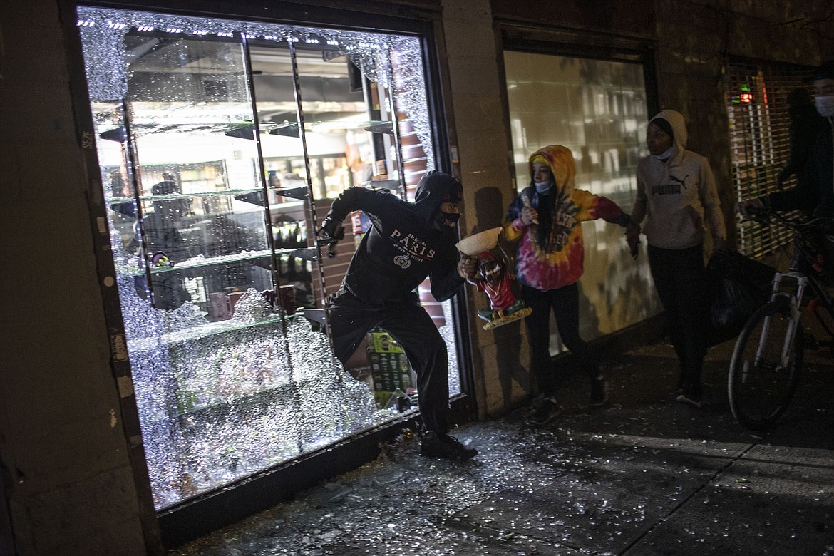 People run out of a smoke shop with smoking instruments after breaking in as police arrive on Monday, June 1, 2020, in New York. Protests were held throughout the city over the death of George Floyd, a black man in police custody in Minneapolis who died after being restrained by police officers on Memorial Day. (AP Photo/Wong Maye-E)