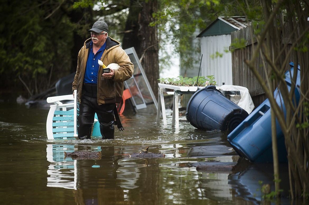 Mark Musselman brings a chair to the front of his house from the back yard, wading through floodwater, Tuesday, May 19, 2020 in Edenville, Mich. People living along two mid-Michigan lakes and parts of a river have been evacuated following several days of heavy rain that produced flooding and put pressure on dams in the area. (Katy Kildee/Midland Daily News via AP)