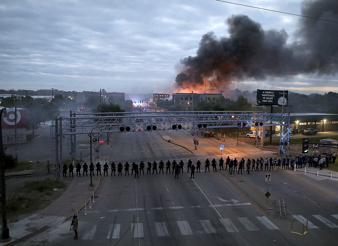 Law enforcement officers amassed along Lake Street near Hiawatha Ave. as fires burned after a night of unrest and protests in the death of George Floyd early Friday, May 29, 2020 in Minneapolis.   Floyd died after being restrained by Minneapolis police officers on Memorial Day. (David Joles/Star Tribune via AP)