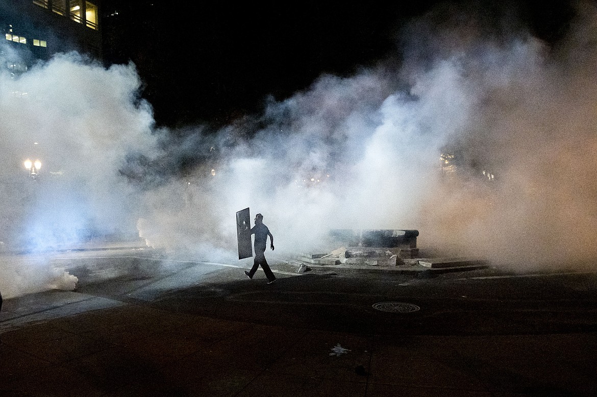 A Black Lives Matter protester carries a shield while facing off against federal officers at the Mark O. Hatfield United States Courthouse on Monday, July 20, 2020, in Portland, Ore. Officers used teargas and projectiles to move the crowd after some protesters tore down a fence fronting the courthouse. (AP Photo/Noah Berger)