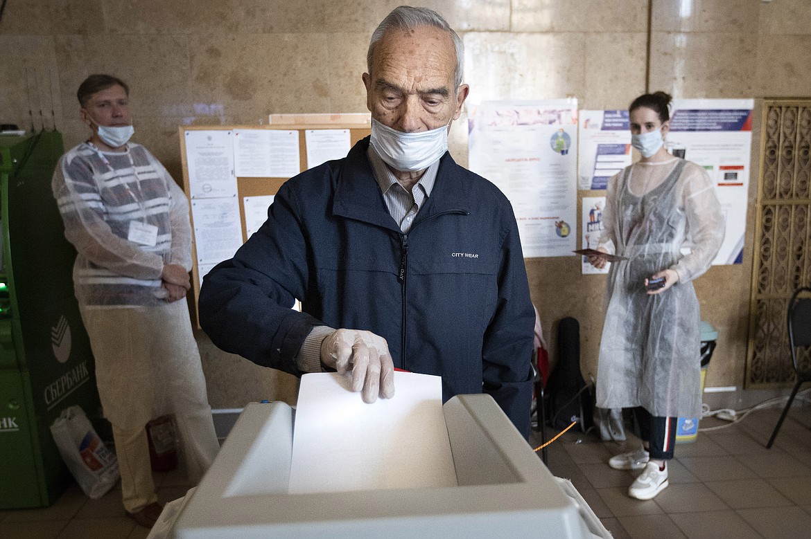 A man wearing a face mask and gloves to protect against coronavirus casts his ballot at a polling station in Moscow, Russia, Wednesday, July 1, 2020. The vote on the constitutional amendments that would reset the clock on Russian President Vladimir Putin's tenure and enable him to serve two more six-year terms is set to wrap up Wednesday. (AP Photo/Alexander Zemlianichenko)
