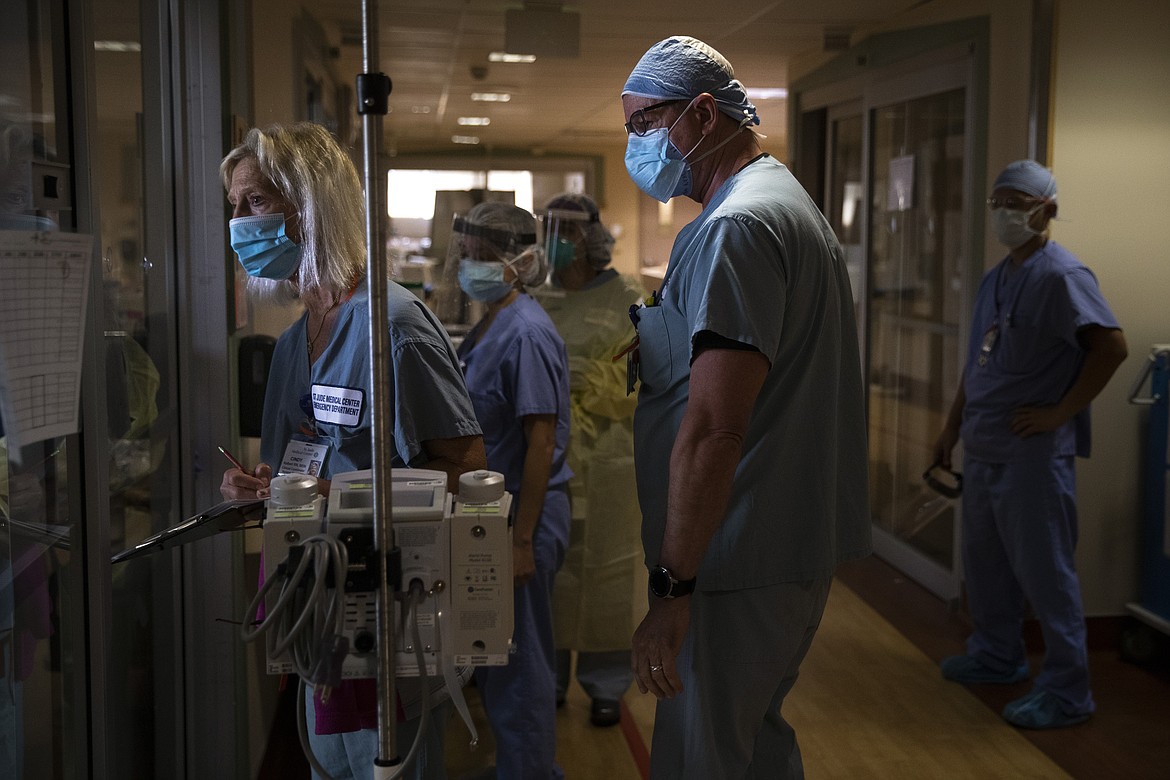 Nurse Cindy Kelbert, left, checks on a critically ill COVID-19 patient through a glass door as she is surrounded by other nurses at St. Jude Medical Center in Fullerton, Calif., Tuesday, July 7, 2020. (AP Photo/Jae C. Hong)