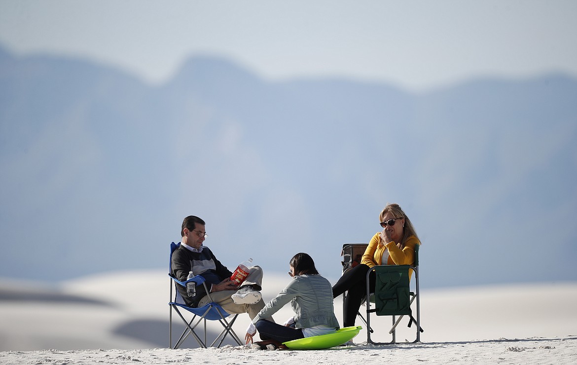 In this March 5, 2020, photograph, visitors relax on a gypsum dune in White Sands National Park at Holloman Air Force Base, N.M. Most national parks are open as a refuge for Americans tired of being stuck at home because of the coronavirus. Entry fees have been eliminated, but many parks are closing visitor centers, shuttles and lodges to fight the spread of the virus. (AP Photo/David Zalubowski)