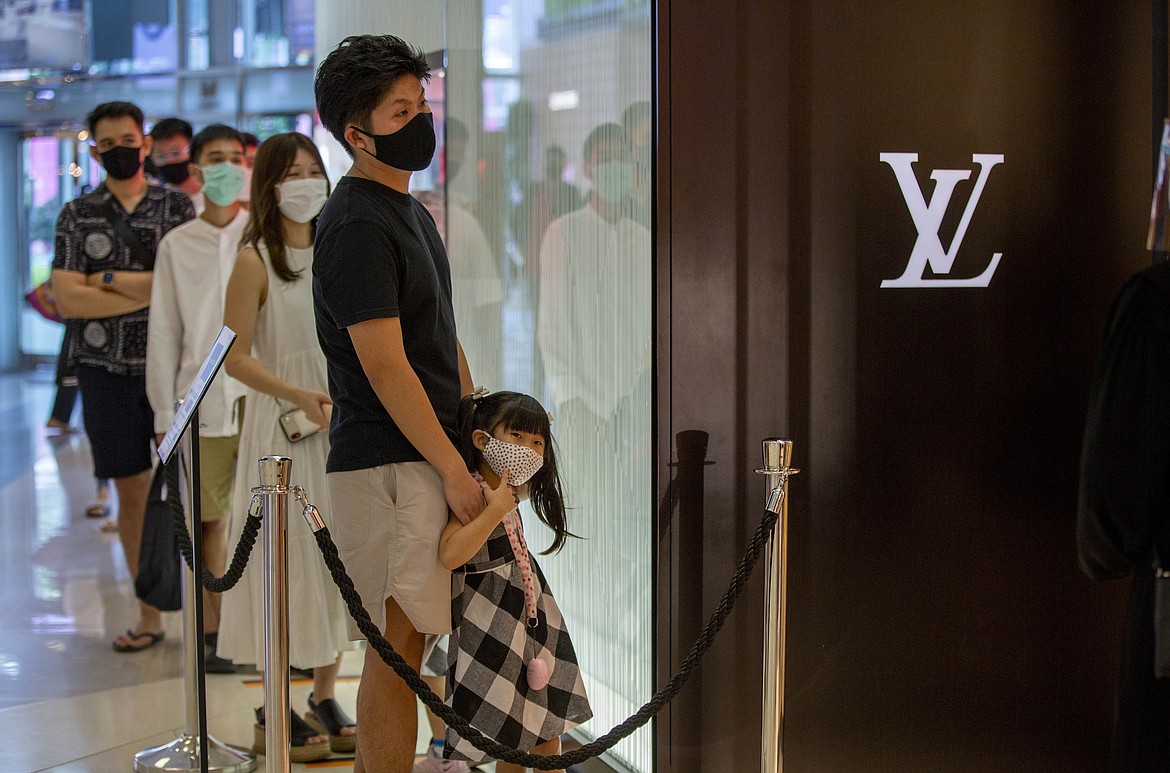 Patrons stand in a line to enter the Louis Vuitton shop at the upmarket shopping mall Siam Paragon in Bangkok, Thailand, Sunday, May 17, 2020. Thai authorities allowed department stores, shopping malls and other businesses to reopen from Sunday, selectively easing restrictions meant to combat the coronavirus. (AP Photo/ Gemunu Amarasinghe)