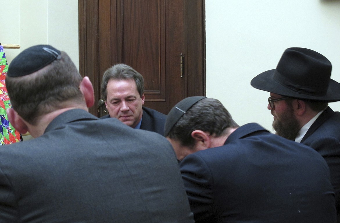 Montana Gov. Steve Bullock, center, listens as a delegation of Orthodox Jewish rabbis thanks him Wednesday, Jan. 18, 2017, in Helena, Mont. The rabbis from across the U.S. and Canada say Bullock and state leaders defended the Jewish community in Whitefish, Mont., when it was threatened and harassed by white supremacists last month. (AP Photo/Matt Volz)