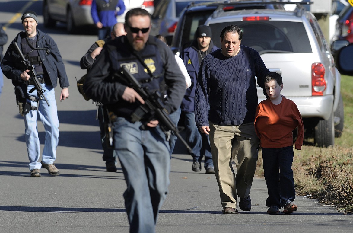 FILE - In this Friday, Dec. 14, 2012 file photo, parents leave a staging area after being reunited with their children following a shooting at the Sandy Hook Elementary School in Newtown, Conn., where Adam Lanza fatally shot 27 people, including 20 children. The Republican-led Senate voted Wednesday, Feb. 15, 2017, to block an Obama-era regulation that would prevent an estimated 75,000 people with mental disorders from being able to purchase a firearm. (AP Photo/Jessica Hill, File)