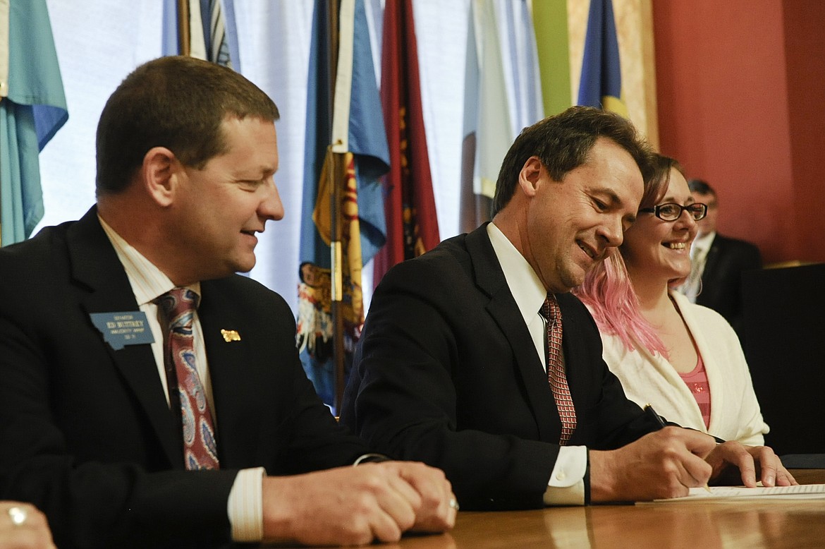 FILE - In this April 29, 2015 file photo, Democratic Gov. Steve Bullock, center, signs a bill to expand Medicaid, at the Capitol in Helena, Mont., as bill sponsor Republican state Sen. Ed Buttrey looks on. Buttrey is a contender for the Republican Party's nomination in a special election to fill Montana's seat in the U.S. House which became vacant Wednesday, March 1, 2017 when Republican Ryan Zinke was confirmed as President Donald Trump's Interior Department secretary. (Thom Bridge/Independent Record via AP, file)