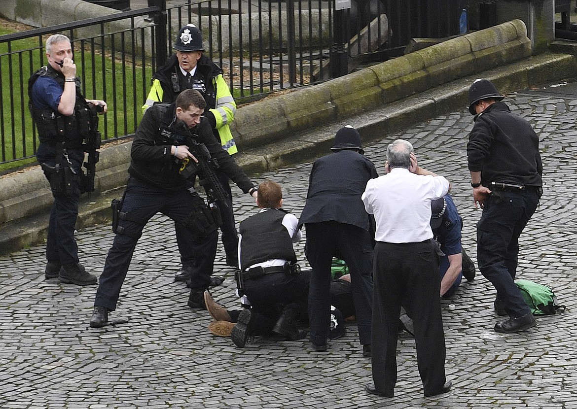 A policeman points a gun at a man on the floor as emergency services attend the scene outside the Palace of Westminster, London, Wednesday, March 22, 2017.  London police say they are treating a gun and knife incident at Britain&#146;s Parliament &#147;as a terrorist incident until we know otherwise.&#148; The Metropolitan Police says in a statement that the incident is ongoing. It is urging people to stay away from the area. Officials say a man with a knife attacked a police officer at Parliament and was shot by officers. Nearby, witnesses say a vehicle struck several people on the Westminster Bridge.  (Stefan Rousseau/PA via AP).