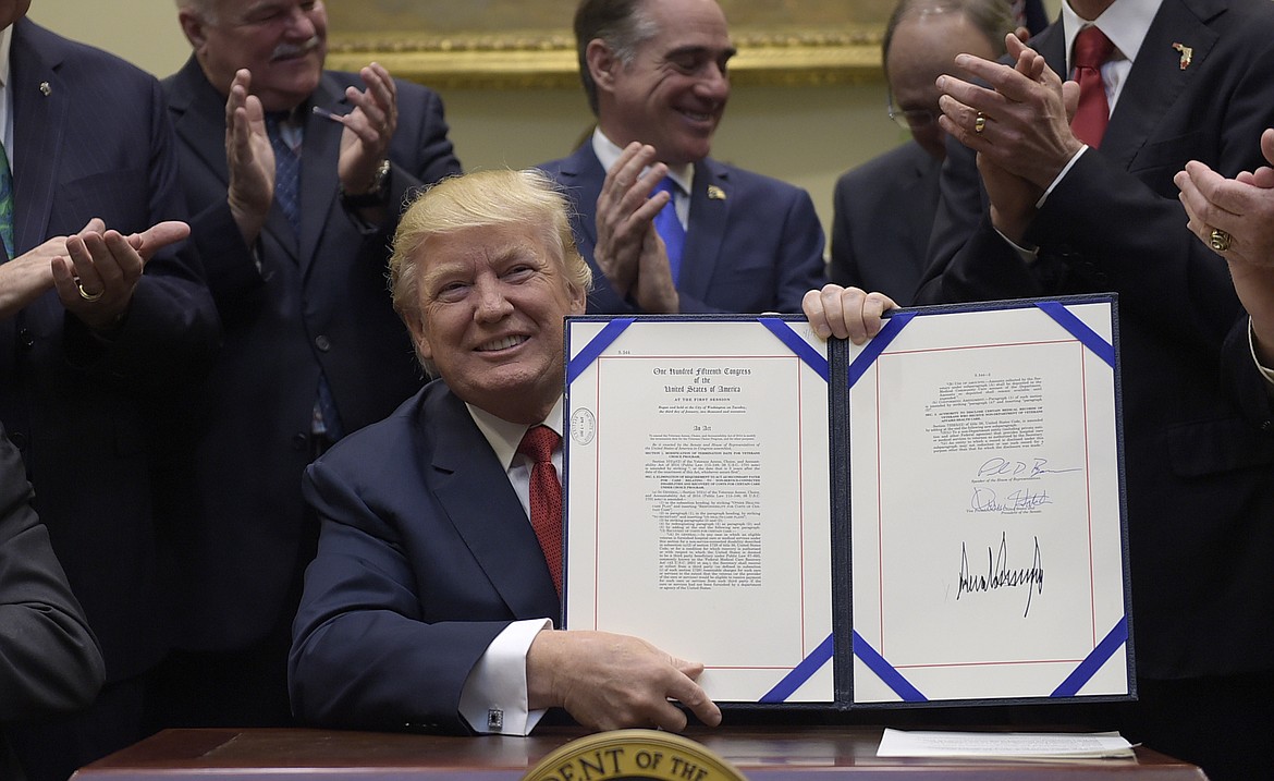 President Donald Trump hold up the Veterans Choice Program Extension and Improvement Act that he signed,  Wednesday, April 19, 2017, in the Roosevelt Room of the White House in Washington. (AP Photo/Susan Walsh)