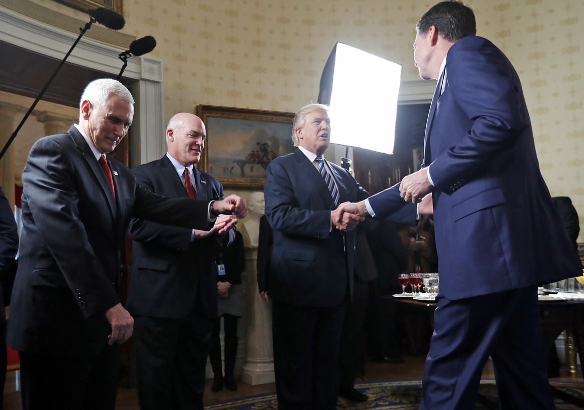 FILE - In this this Jan. 22, 2017, file photo, Vice President Mike Pence, left, and Secret Service Director Joseph Clancy stand as President Donald Trump shakes hands with then-FBI Director James Comey during a reception for inaugural law enforcement officers and first responders in the Blue Room of the White House in Washington. Fired FBI Director James Comey&#146;s gripping written account of his private encounters with Donald Trump since January reads like a movie script. (AP Photo/Alex Brandon)