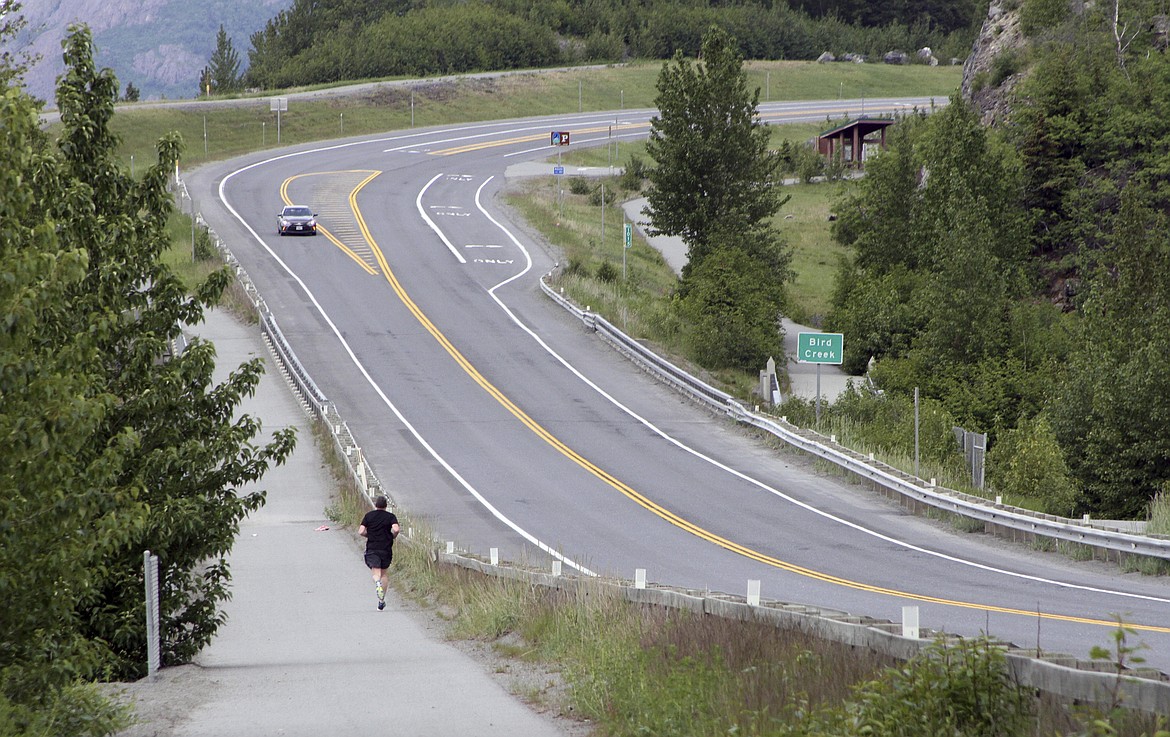 A jogger runs across the Sterling Highway from the Bird Creek access point, near a trail head that's closed on Monday, June 19, 2017, after a fatal bear mauling at Bird Ridge Trail in Anchorage, Alaska. Authorities say a black bear killed a 16-year-old runner while he was competing in an Alaska race on Sunday. (AP Photo/Mark Thiessen)