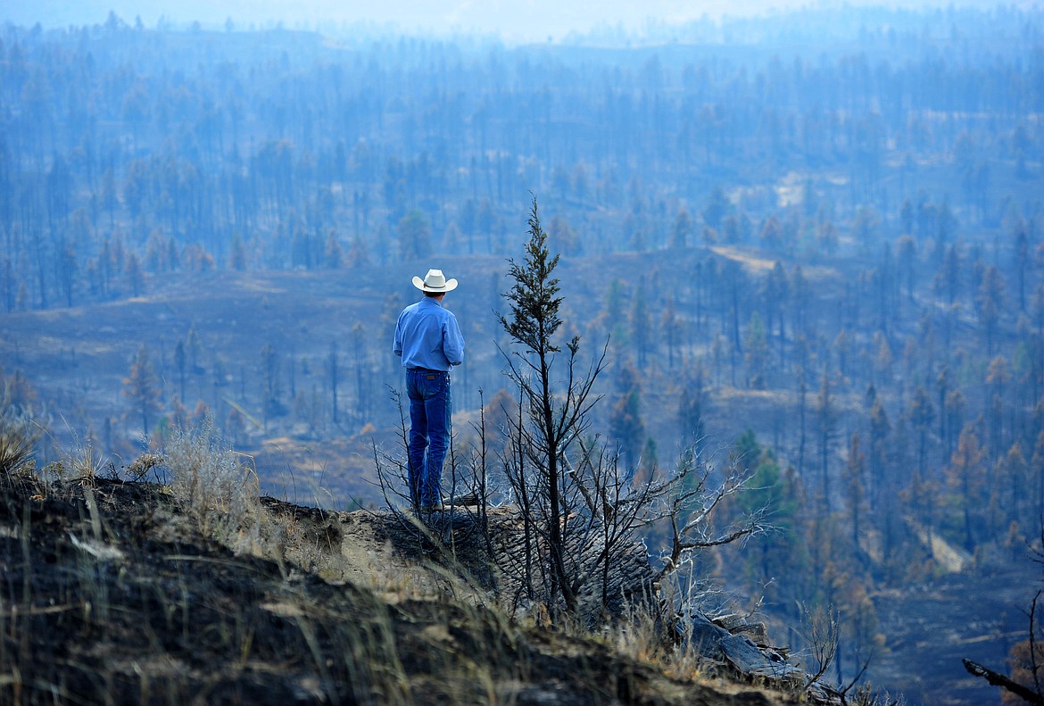 Tim Weyer tours his ranch, which was consumed by wildfires, Tuesday, July 25, 2017 in Sand Springs, Mont.  Firefighters say they have stopped most of the growth and gained 20 percent containment on the fires that were started last week by lightning.  (Rion Sanders/The Great Falls Tribune via AP)