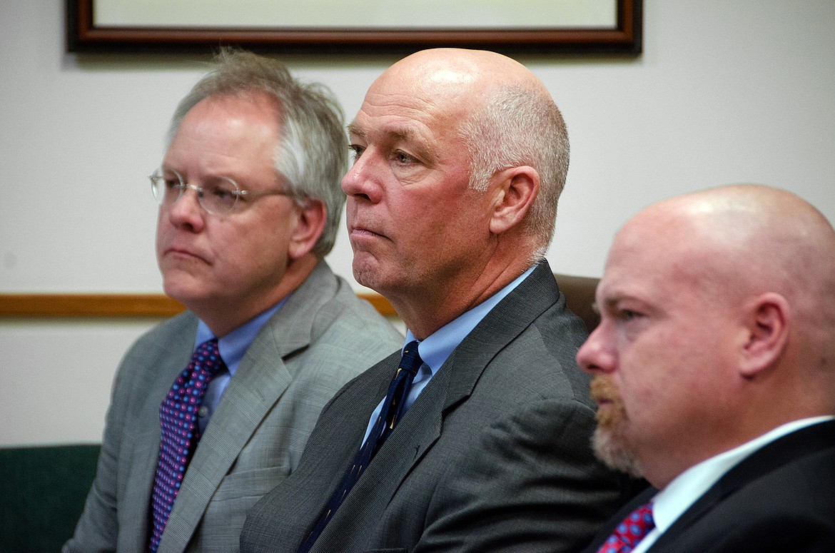 FILE - In this June 12, 2017 file photo, Congressman-elect Greg Gianforte, center, sits alongside William Mercer, left, and Todd Whipple during his court hearing in Bozeman, Mont. Gianforte has been photographed and fingerprinted after pleading guilty to assaulting a reporter on the eve of the special election that put him in office. Gallatin County jail records indicate the booking process Friday, Aug. 25, 2017 took 23 minutes, beginning at 6:37 a.m. (Freddy Monares/Bozeman Daily Chronicle via AP, File)