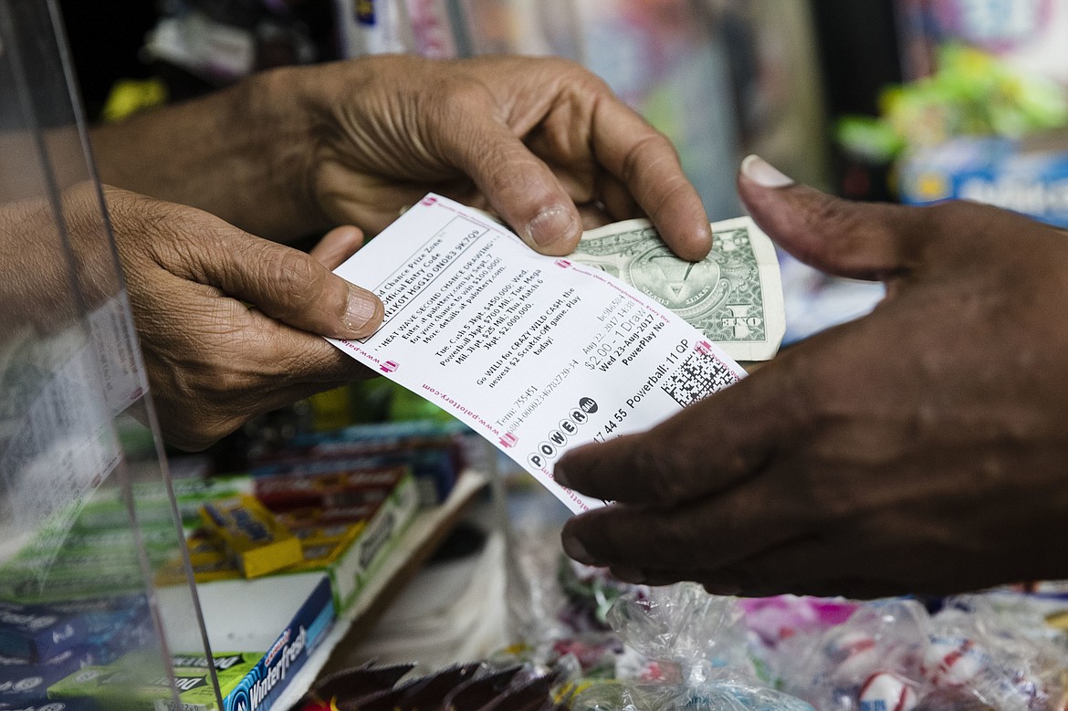 Atul Amin, left, sells a customer a Powerball ticket at his news stand in Philadelphia, Tuesday, Aug. 22, 2017. (AP Photo/Matt Rourke)