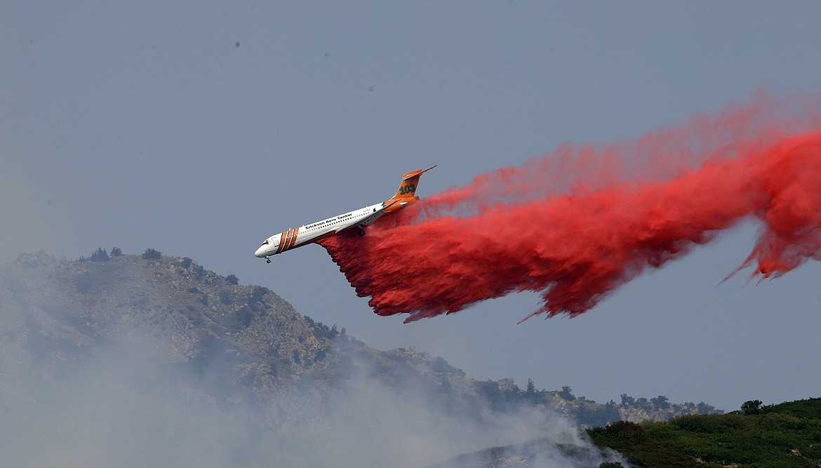 A heavy tanker drops retardant on a wildfire in Weber Canyon, Tuesday, Sept. 5, 2017, near Ogden, Utah. At least one home went up in smoke and more than 1,000 people were evacuated as high winds fed the flames that started in a canyon north of Salt Lake City. (AP Photo/Rick Bowmer)