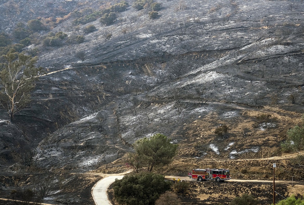 A fire engine drives past a burned area from a wildfire Monday, Sept. 4, 2017, in the Sunland-Tujunga section of Los Angeles. (AP Photo/Ringo H.W. Chiu)