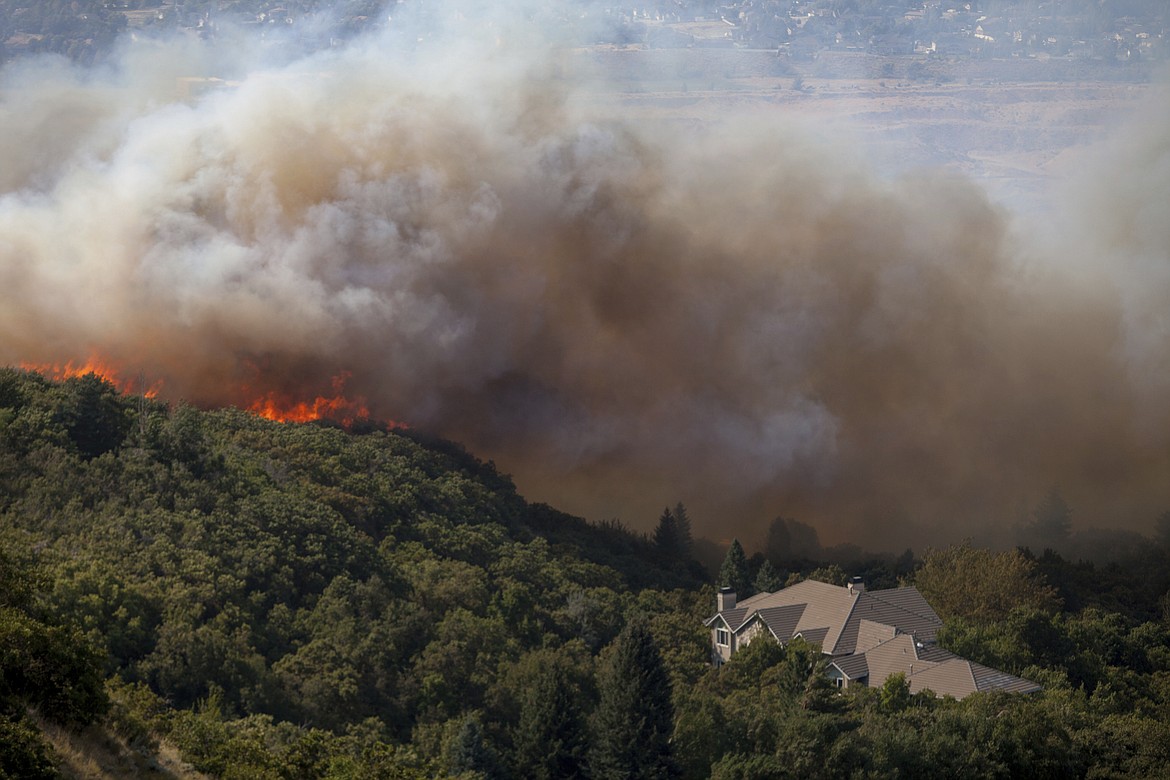 In this Tuesday, Sept. 5, 2017, photo, a wildfire burns through residential areas near the mouth of Weber Canyon near Ogden, Utah. (Benjamin Zack/Standard-Examiner via AP)