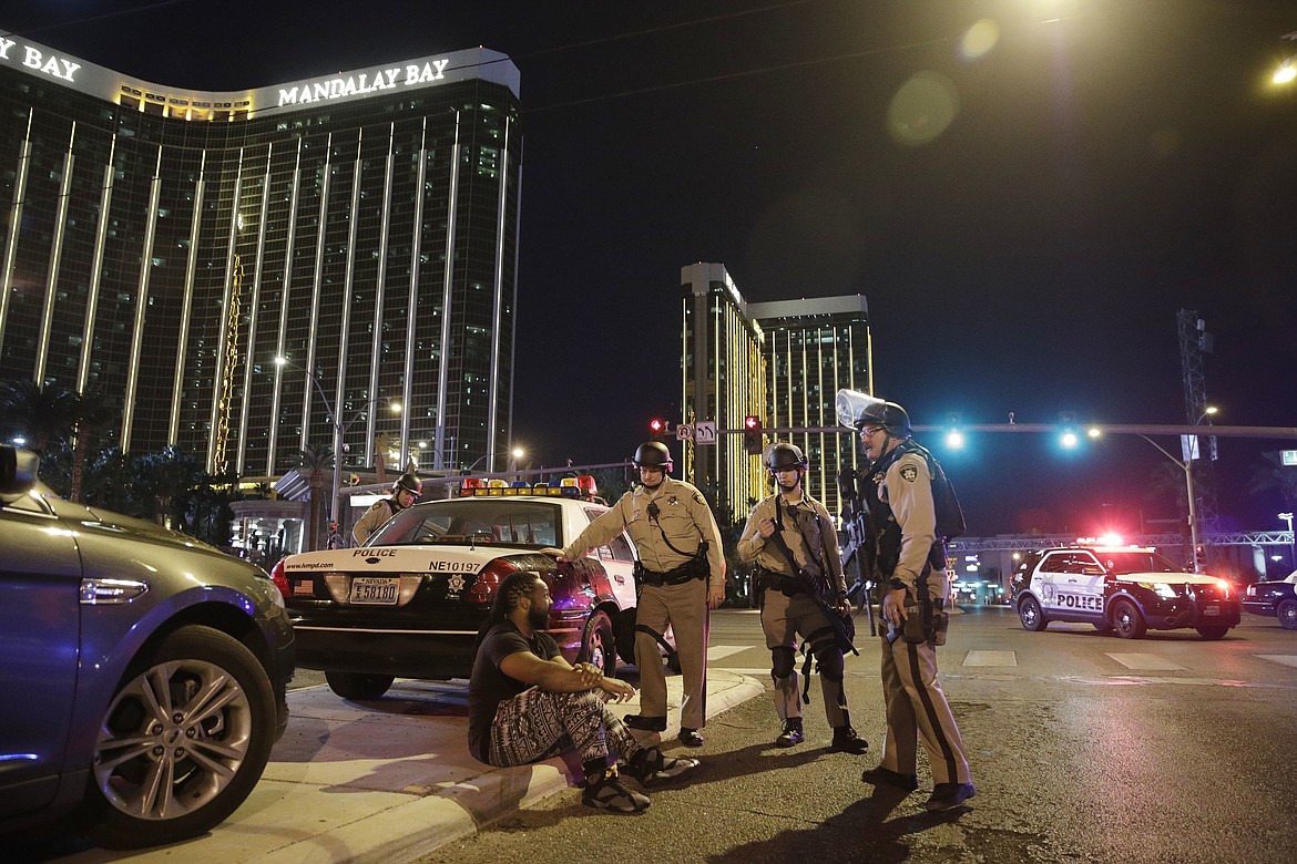 Police officers stand at the scene of a shooting near the Mandalay Bay resort and casino on the Las Vegas Strip, Sunday, Oct. 1, 2017, in Las Vegas. Multiple victims were being transported to hospitals after a shooting late Sunday at a music festival on the Las Vegas Strip.  (AP Photo/John Locher)