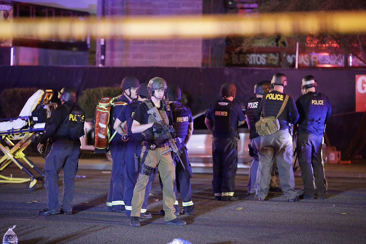 Police officers and medical personnel stand at the scene of a shooting near the Mandalay Bay resort and casino on the Las Vegas Strip, Monday, Oct. 2, 2017, in Las Vegas. Multiple victims were being transported to hospitals after a shooting late Sunday at a music festival on the Las Vegas Strip. (AP Photo/John Locher)