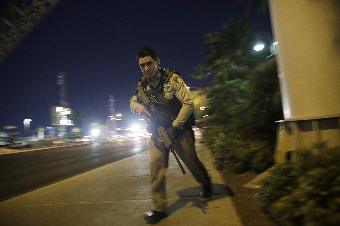 A police officer runs along a sidewalk near a shooting near the Mandalay Bay resort and casino on the Las Vegas Strip, Sunday, Oct. 1, 2017, in Las Vegas. (AP Photo/John Locher)