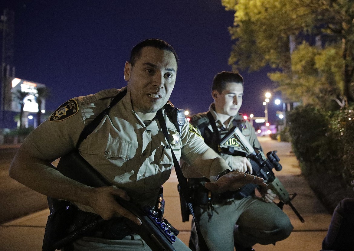 Police officers advise people to take cover near the scene of a shooting near the Mandalay Bay resort and casino on the Las Vegas Strip, Sunday, Oct. 1, 2017, in Las Vegas. (AP Photo/John Locher)