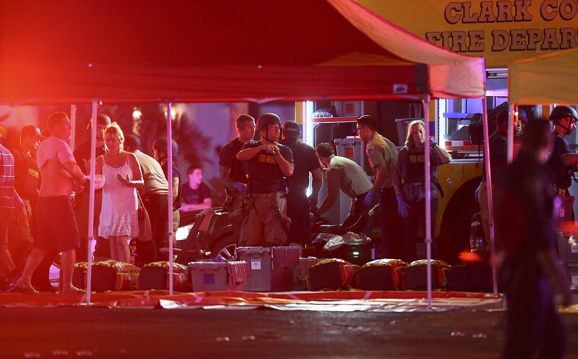 Medics treat the wounded as Las Vegas police respond during an active shooter situation on the Las Vegas Stirp in Las Vegas Sunday, Oct. 1, 2017. Multiple victims were being transported to hospitals after a shooting late Sunday at a music festival on the Las Vegas Strip. (Chase Stevens/Las Vegas Review-Journal via AP)