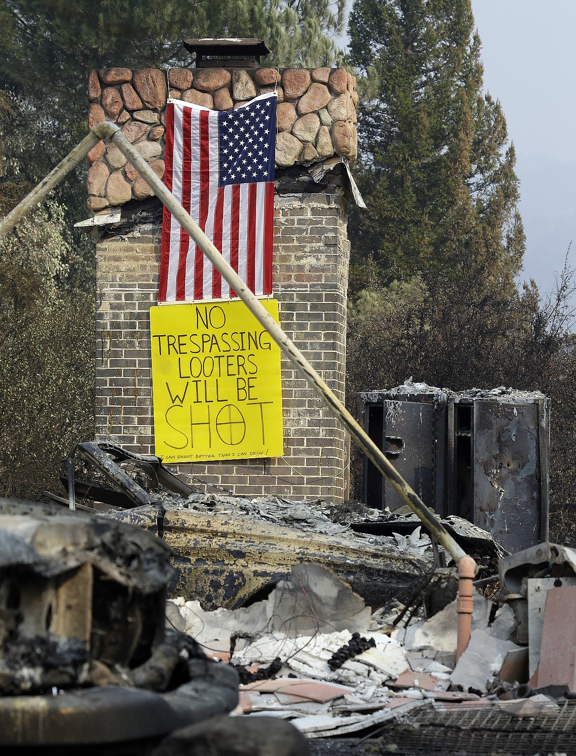 A sign warning looters will be shot is seen on the chimney of a home destroyed by wildfires on Wednesday, Oct. 18, 2017, in Glen Ellen, Calif. California fire officials have reported significant progress on containing wildfires that have ravaged parts of Northern California. The fires that swept through parts of seven counties starting Oct. 8 were the deadliest and most destructive series of blazes in California history.  (AP Photo/Ben Margot)