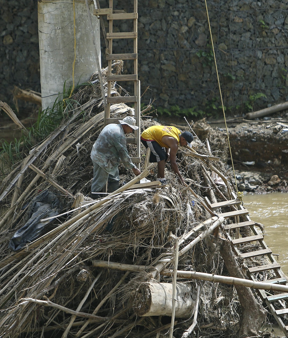 In this Friday, Oct. 27, 2017 photo, Rio Abajo residents, Carlos Ocasio Borrero, left, and Luis Santiago clean up debris in Utuado as recovery efforts from Hurricane Maria continue in Puerto Rico. (David Santiago/Miami Herald via AP)