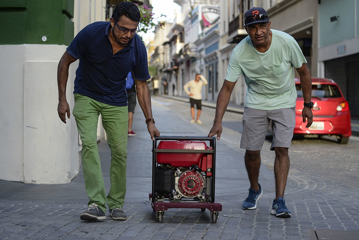 In this Friday, Oct. 20, 2017 photo, men push a generator along Fortaleza street, one month after Hurricane Maria in San Juan, Puerto Rico. Maria roared across the island on Sept. 20 and after a month, only 30 percent of residents have power. (AP Photo/Carlos Giusti)