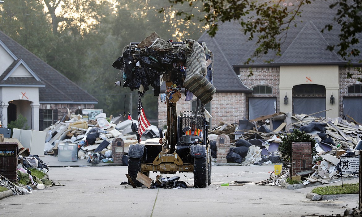 FILE - In this Sept. 26, 2017, file photo, a worker cleans up debris in a neighborhood flooded by Hurricane Harvey in Beaumont, Texas. If House Republicans have their way, victims of hurricanes in Texas and Florida could deduct their losses on their taxes. But victims of the California wildfires no longer could. (AP Photo/David Goldman, File)