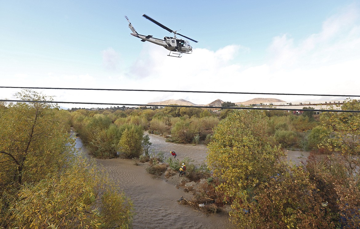 A women is hoisted out with the help of a San Bernardino County Sheriff&#146;s helicopter on Tuesday, Jan. 9, 2018, in the Santa Ana River and near the borders of Rialto, Colton, and Riverside, Calif. Three people and a dog were rescued by a helicopter after large amounts of rain fell, trapping the group at a homeless encampment in the river. (Stan Lim/Los Angeles Daily News via AP)