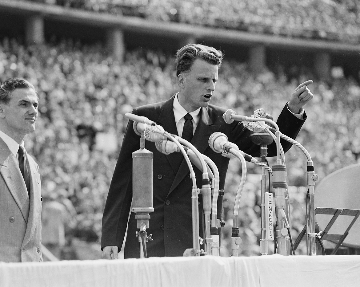 FILE - In this June 27, 1954 file photo, Evangelist Billy Graham speaks to over 100,000 Berliners at the Olympic Stadium in Berlin, Germany.   Graham, who transformed American religious life through his preaching and activism, becoming a counselor to presidents and the most widely heard Christian evangelist in history, has died. Spokesman Mark DeMoss says Graham, who long suffered from cancer, pneumonia and other ailments, died at his home in North Carolina on Wednesday, Feb. 21, 2018. He was 99. (AP Photo, File)