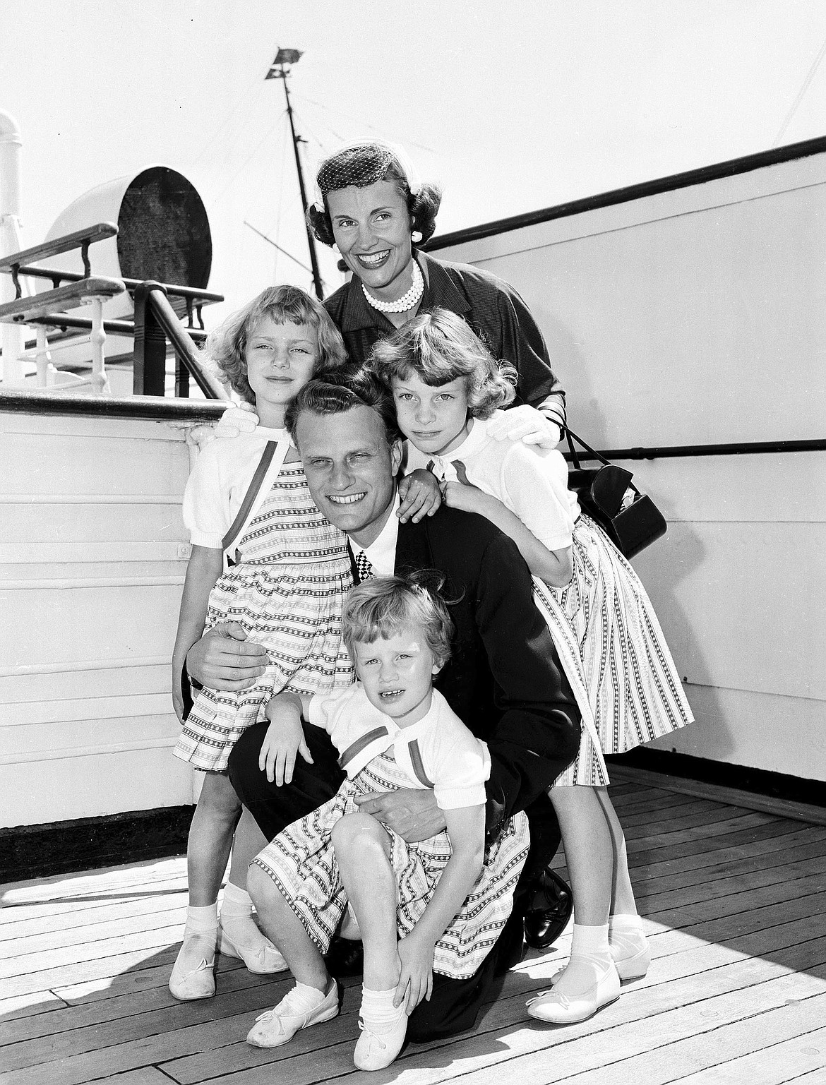 FILE - In this July 7, 1954 file photo,  Evangelist Billy Graham poses with his his wife, Ruth, and their three daughters on the Queen Mary following his arrival in New York.   Graham, who transformed American religious life through his preaching and activism, becoming a counselor to presidents and the most widely heard Christian evangelist in history, has died. Spokesman Mark DeMoss says Graham, who long suffered from cancer, pneumonia and other ailments, died at his home in North Carolina on Wednesday, Feb. 21, 2018. He was 99.(AP Photo)