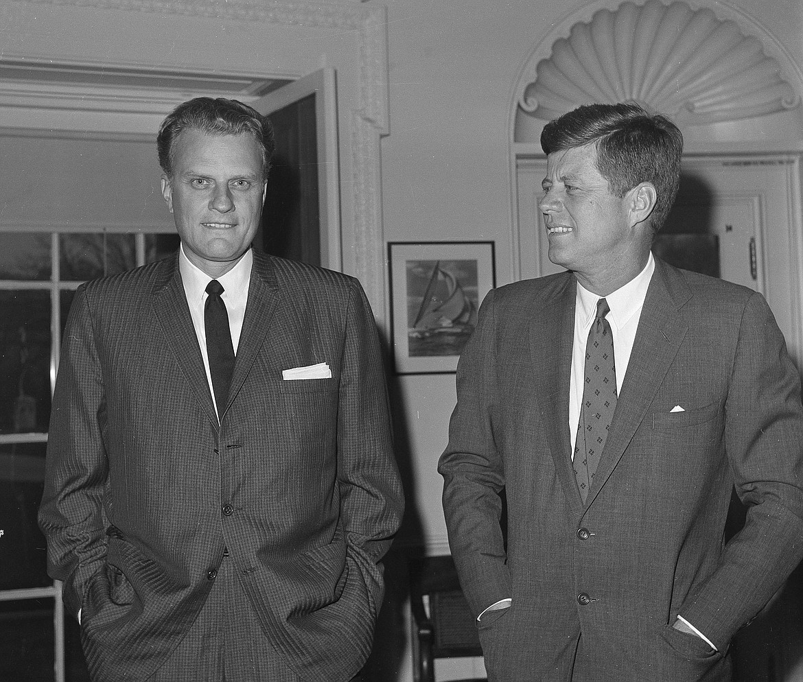 FILE - In this Dec. 12, 1961 file photo,  Evangelist Billy Graham, left, talks with President John F. Kennedy during a call at the the White House in Washington.   Graham, who transformed American religious life through his preaching and activism, becoming a counselor to presidents and the most widely heard Christian evangelist in history, has died. Spokesman Mark DeMoss says Graham, who long suffered from cancer, pneumonia and other ailments, died at his home in North Carolina on Wednesday, Feb. 21, 2018. He was 99. (AP Photo, File)