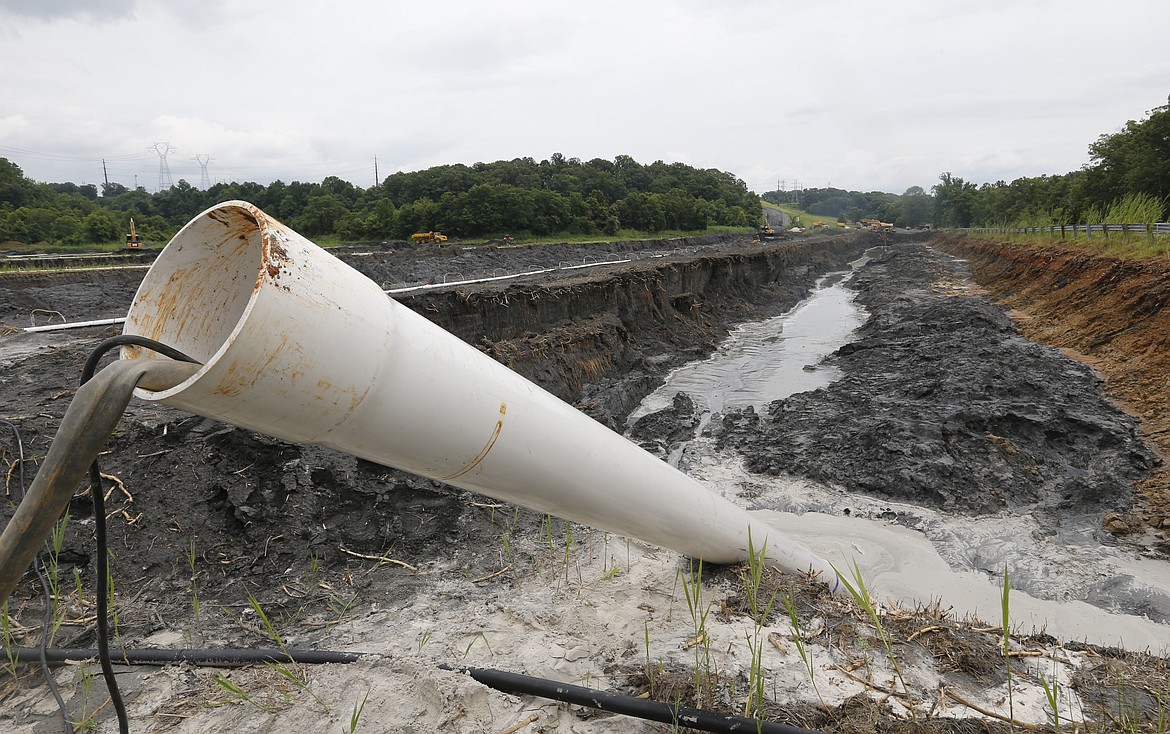 FILE - In this Friday June 26, 2015 file photo, a drain pipe sticks out of a coal ash retention pond at the Dominion Power's Possum Point Power Station in Dumfries, Va. Major utilities are finding evidence of groundwater contamination at coal-burning power plants across the U.S. where landfills and man-made ponds have been used for decades as dumping grounds for coal ash. Data the utilities must publish by Friday, March 2, 2018, show heightened levels of arsenic, radium and other hazardous materials have been found at plants in numerous states, from Virginia and North Carolina to Montana and Alaska. (AP Photo/Steve Helber, File)