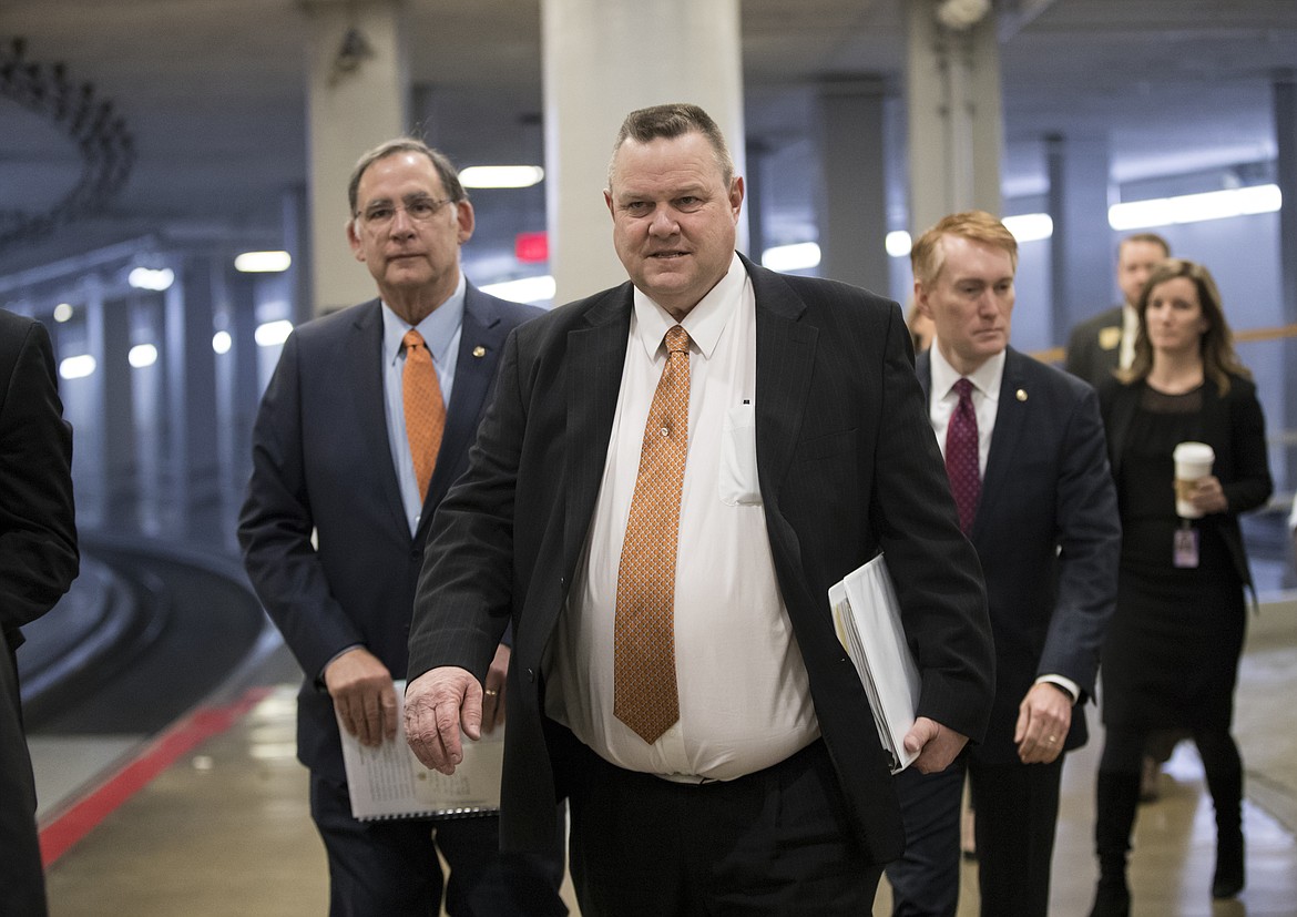 FILE - In this March 6, 2018, file photo, Sen. Jon Tester, D-Mont., flanked by Sen. John Boozman, R-Ark., left, and Sen. James Lankford, R-Okla., arrive with other lawmakers for a procedural vote as the Senate moved to pass legislation that would roll back some of the safeguards Congress put into place after a financial crisis rocked the nation's economy ten years ago at the Capitol in Washington. Tester has repeatedly said the Dodd-Frank regulations led to his state losing many small banks, particularly in rural areas. (AP Photo/J. Scott Applewhite, File)